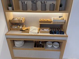 Un bufé de desayuno con panes, bollería y frascos de conservas.