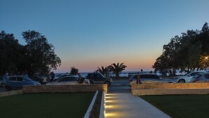 Un sendero pavimentado con una fila de luces, bordeado por césped y un muro de piedra.