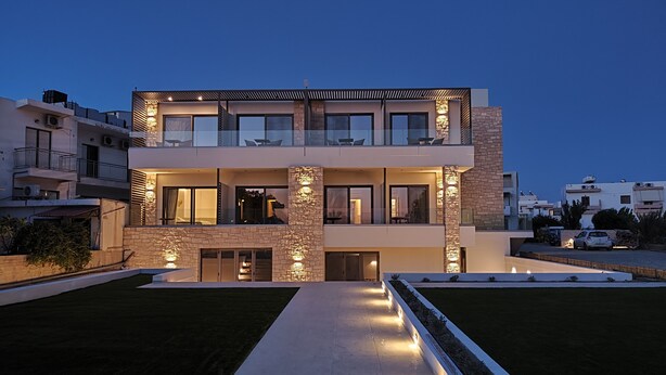 Una casa moderna de dos pisos con un amplio patio delantero, ventanas grandes y una entrada bien iluminada.