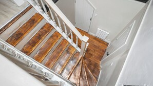Een trap met houten treden en witte balustrades, leidend naar een deur met een witte omlijsting.
