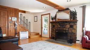 A living room with a stone fireplace, wooden staircase, and a red leather sofa. - ZaLo Manor Unit Lakefront hot tub, pets (Peru)
