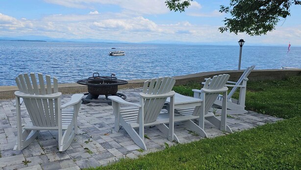 A patio with Adirondack chairs and a fire pit overlooking a body of water. - ZaLo Manor Unit Lakefront hot tub, pets (Peru)