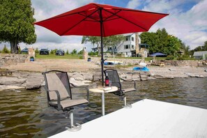 A dock with a red umbrella, two chairs, and a table with a bottle and glass. - ZaLo Manor Unit Lakefront hot tub, pets (Peru)