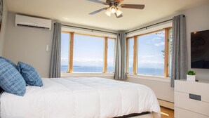 A bedroom with a bed, a ceiling fan, an air conditioning unit, a TV, and a view of the sea. - ZaLo Manor Unit Lakefront hot tub, pets (Peru)