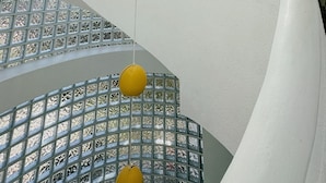 A spiral staircase with a glass enclosure and yellow spherical lights.