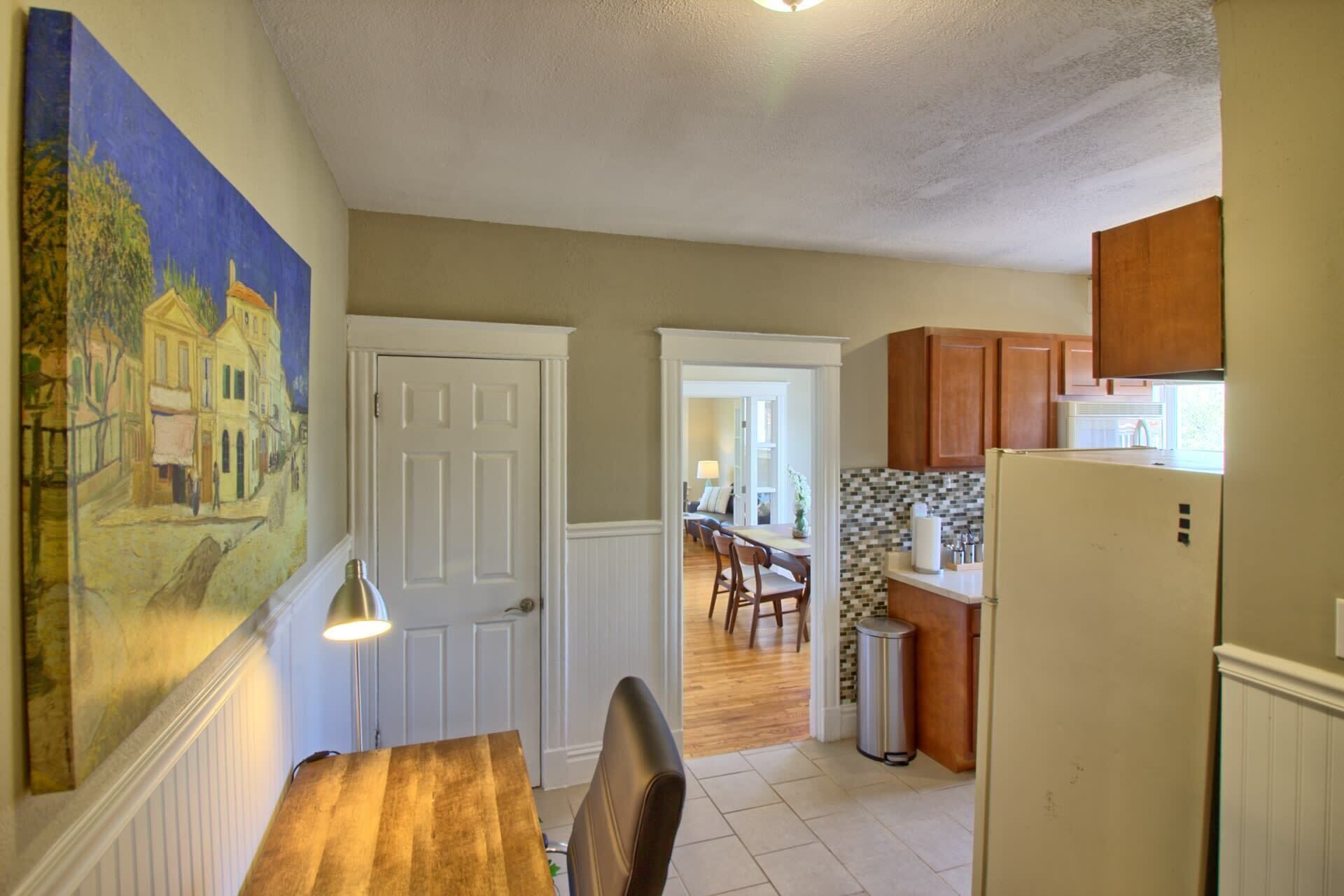 A kitchen with wooden cabinets, a refrigerator, and a dining area with a table and chairs.