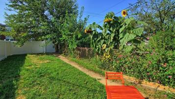 A garden with a wooden bench, a large sunflower plant, and a fence.