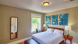 A bedroom with a bed, bedside lamps, a window, and wall art. - Magnolia at TG Park | Free PK+WD+Pet Friendly (Saint Louis)