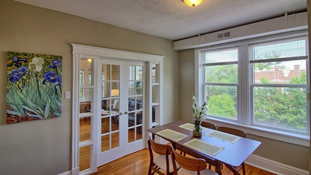 A dining area with a table, chairs, a painting, and a window with blinds. - Magnolia at TG Park | Free PK+WD+Pet Friendly (Saint Louis)