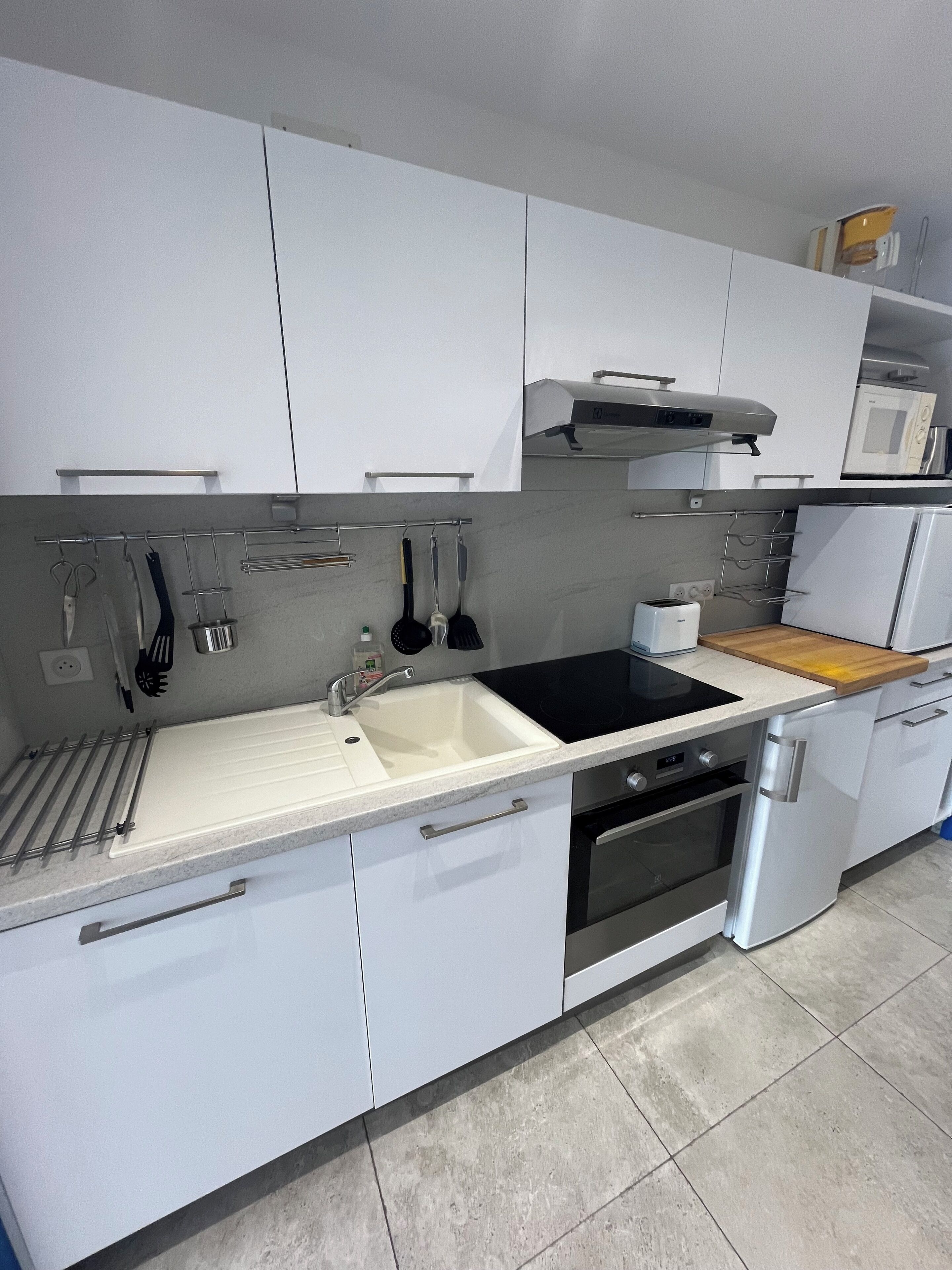 Une cuisine moderne avec des meubles blancs, une cuisinière noire et un four à micro-ondes.