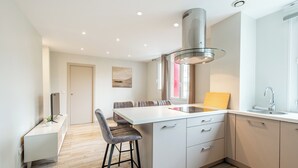 Een moderne keuken met een centraal eiland, een inbouwfornuis en een groot raam.