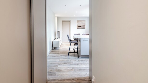 Een moderne keuken met een eetgedeelte, met een houten vloer, witte kasten en een minimalistisch design.