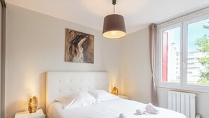 Een moderne hotelkamer met een groot bed, een hoofdbord, een schilderij aan de muur en een raam met uitzicht op gebouwen.