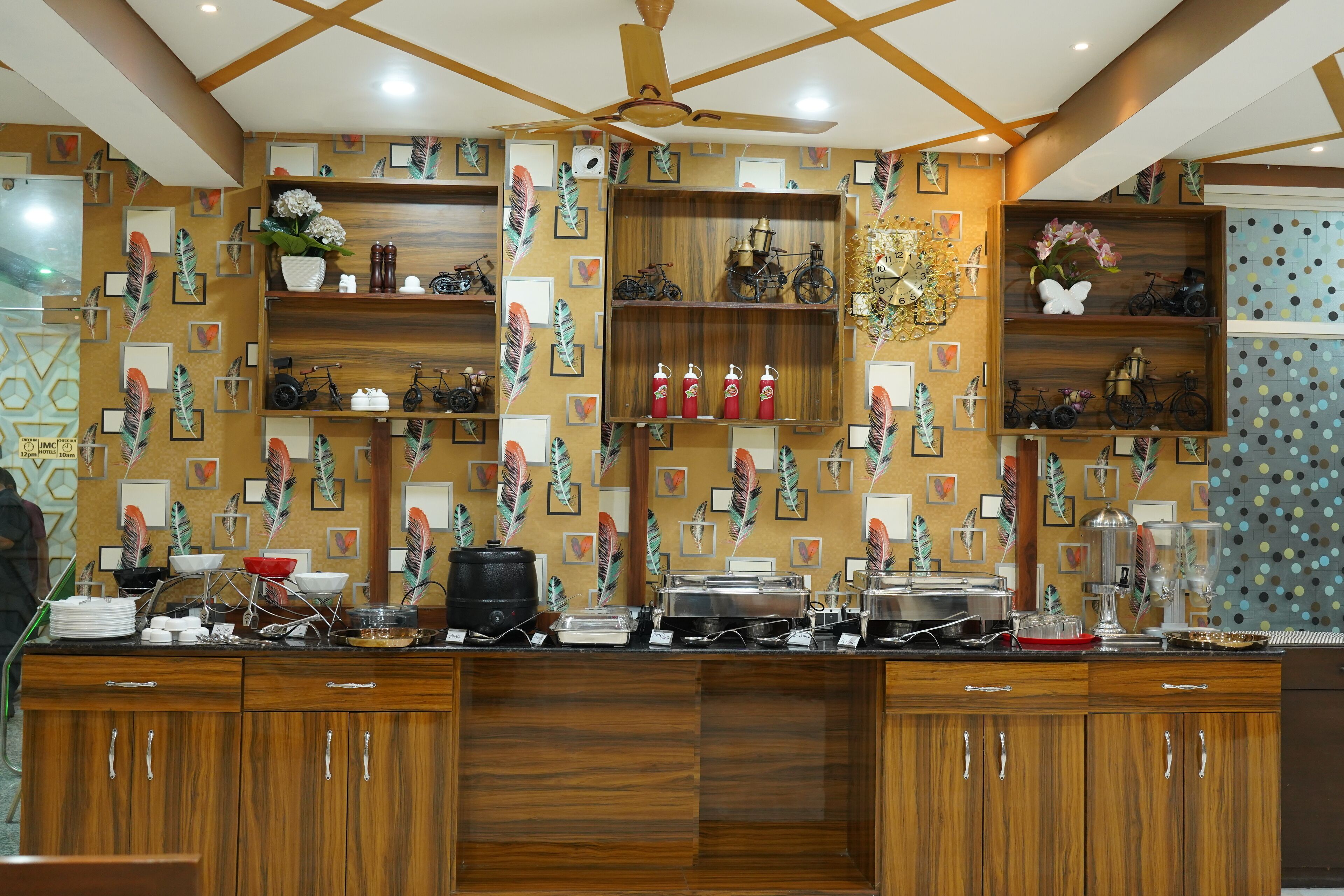 A buffet area with wooden cabinets, shelves with decorative items, and a ceiling fan.