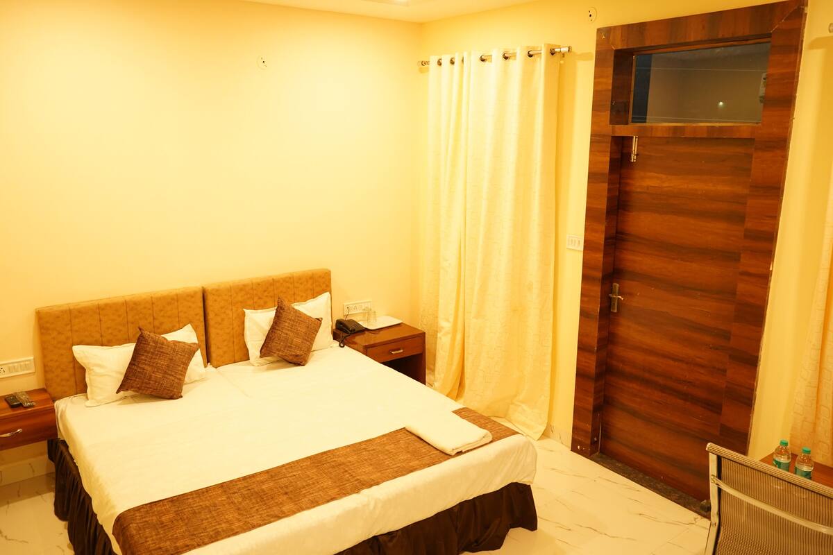 Una habitación de hotel con una cama grande, una puerta de madera y una cortina.
