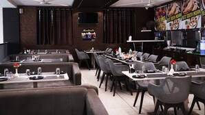 Ein Restaurant mit mehreren Tischen, Sitzgelegenheiten und einer Bar, an der verschiedene Gerichte beworben werden.