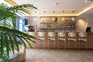 A bar area with a counter, bar stools, a shelf with bottles, and hanging lights. - FİFTY5 SUİTE OTEL (Marmaris)