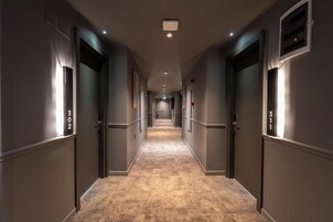 Un pasillo de hotel con pisos alfombrados, puertas numeradas e iluminación empotrada.