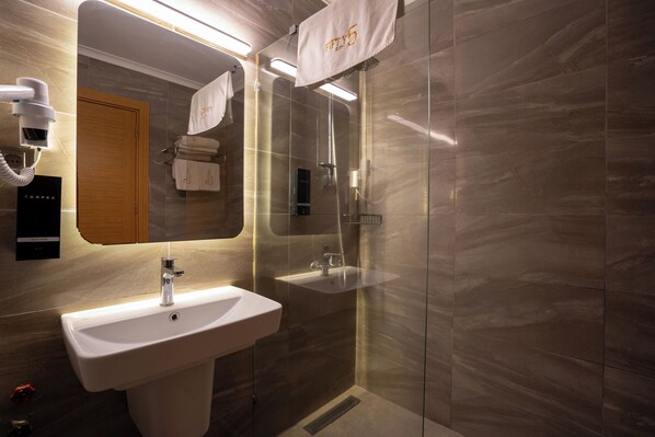 A modern bathroom with a sink, mirror, and shower. - FİFTY5 SUİTE OTEL (Marmaris)