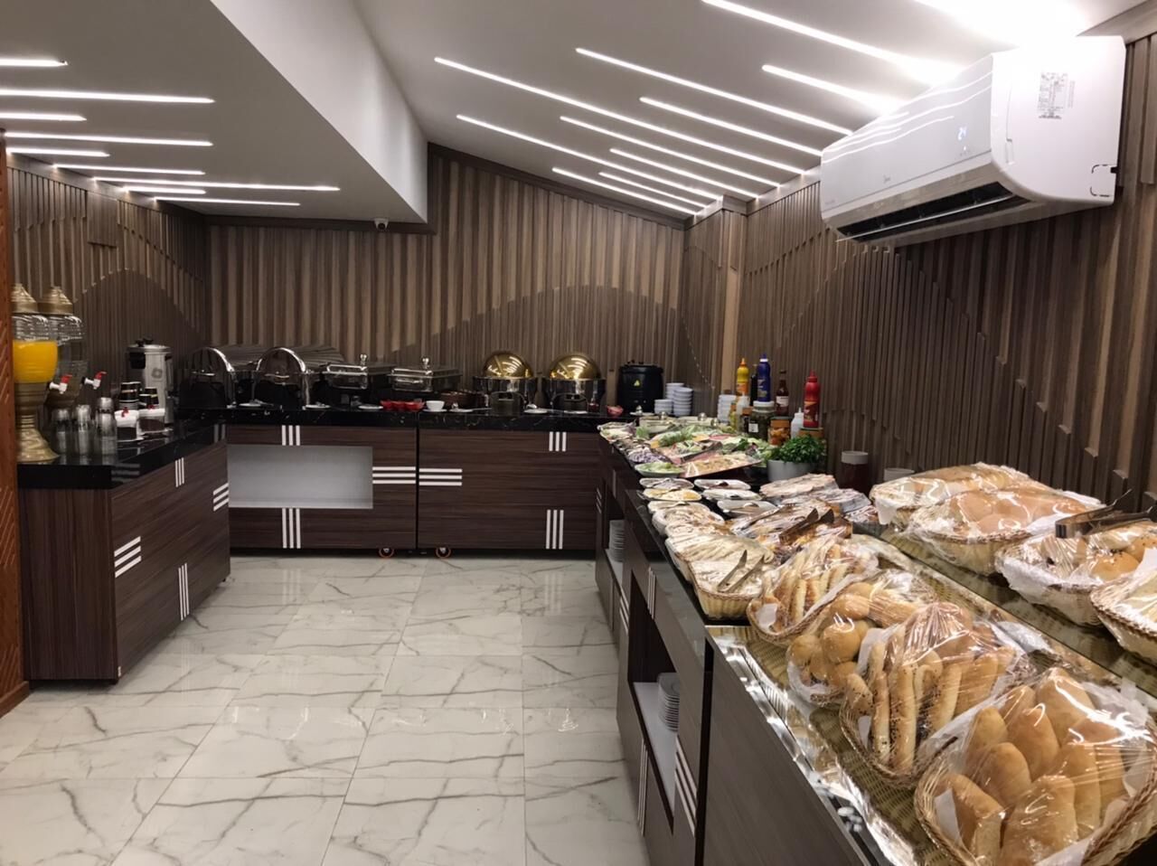 A buffet setup with a variety of food items, a kitchen area with appliances, and a modern interior design.
