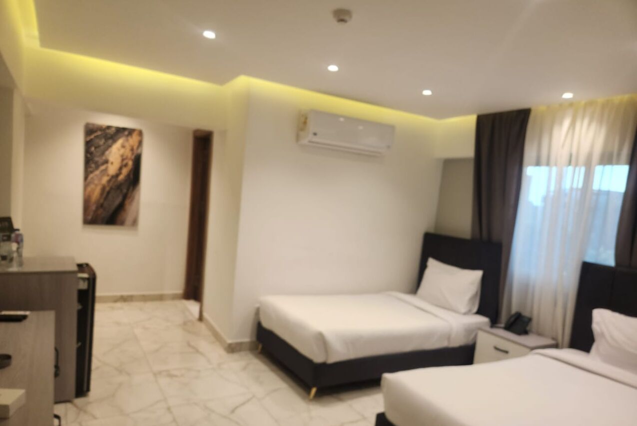 Habitación de hotel con cama, mesitas de noche, escritorio y aire acondicionado.