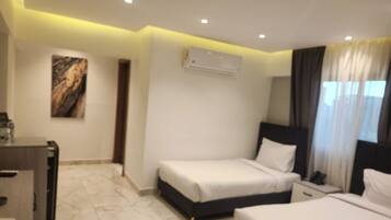 Habitación de hotel con cama, mesitas de noche, escritorio y aire acondicionado.