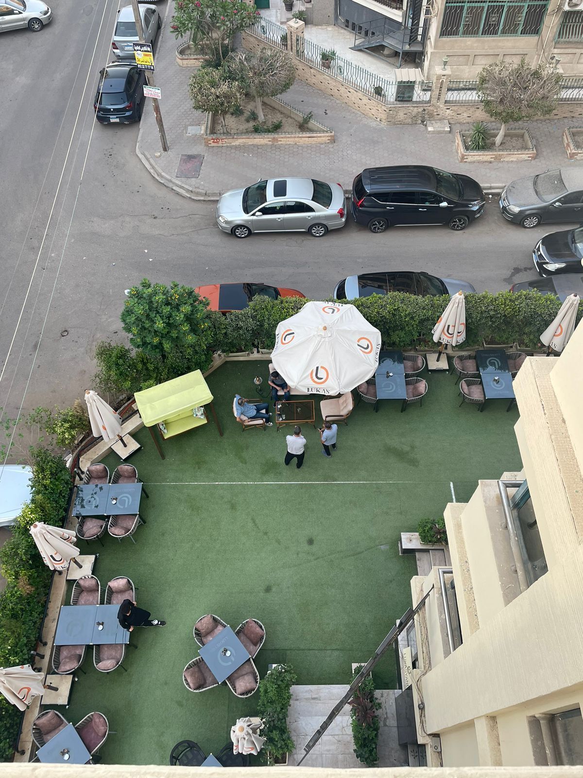 Un espacio al aire libre con mesas, sillas, sombrillas y un pequeño jardín.