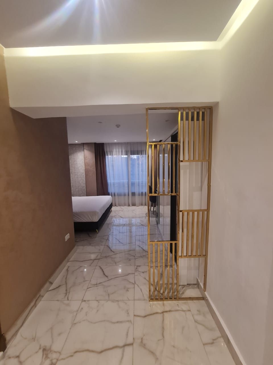 A hotel room with a bed, a mirror, and a marble floor.