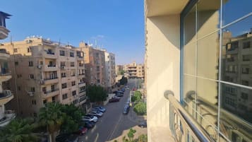A residential street with multi-story buildings, parked cars, and a clear sky.