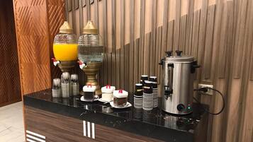 Ein Hotel-Rezeptionsbereich mit einer schwarzen Marmor-Theke, einer Kaffeemaschine und verschiedenen Kaffeetassen und -behältern.