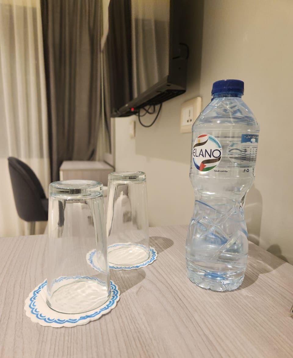 Una mesa con una botella de agua y dos vasos con tapa.