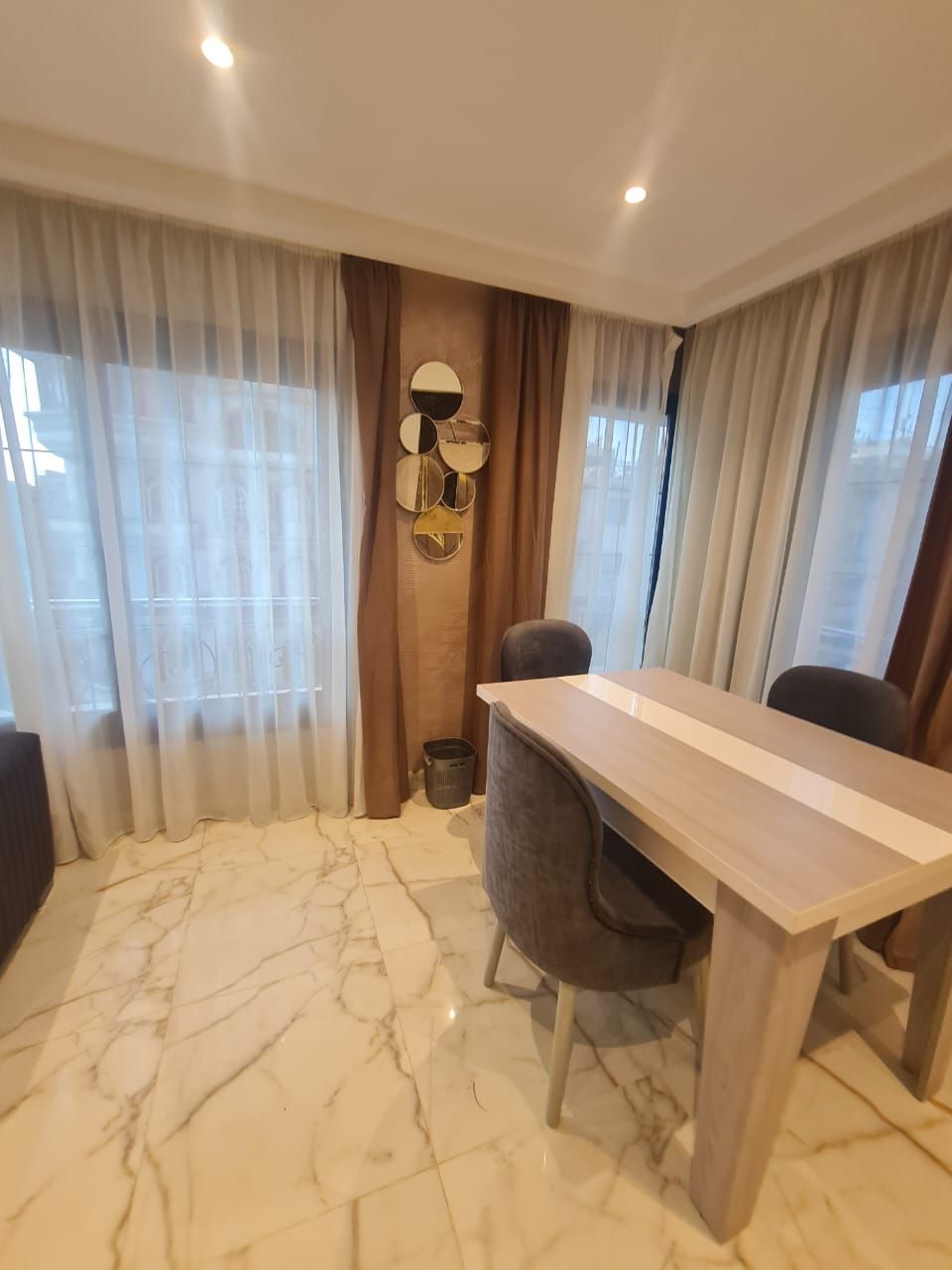 A modern dining area with a marble floor, a wooden table, and two chairs.
