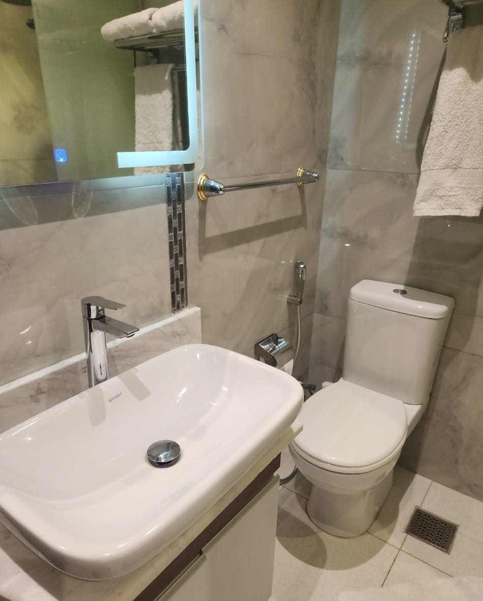 Une salle de bain avec un lavabo blanc, des toilettes et un espace douche.