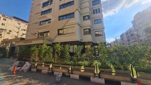 A multi-story building with a flat facade, several windows, and a small garden area with potted plants in the foreground. - el masaadya hotel  (Cairo)