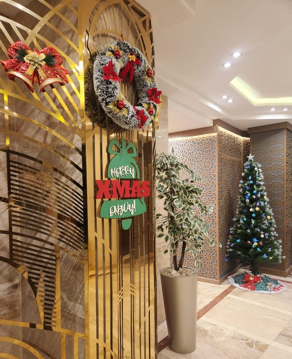 A reception area with a Christmas wreath, a sign reading 'Merry Xmas,' and a Christmas tree.