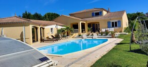 Une maison à deux étages dotée d’une piscine, d’un espace salon extérieur et d’une pergola.