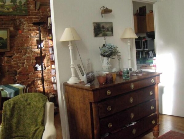 Cozy living room with a rustic brick wall, a wooden dresser, and a comfortable armchair.