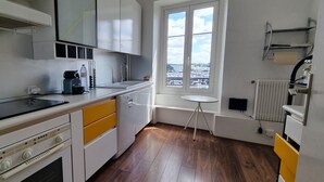 A compact kitchen with a stove, oven, and a small window with a view of buildings.