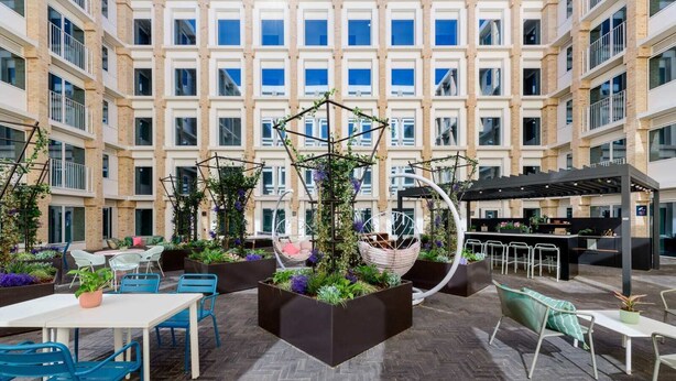 A modern outdoor patio area with seating, planters, and a hanging chair.