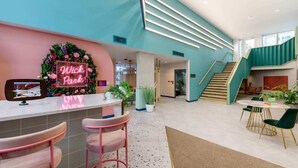 A modern lobby with a reception desk, a staircase, and a seating area.