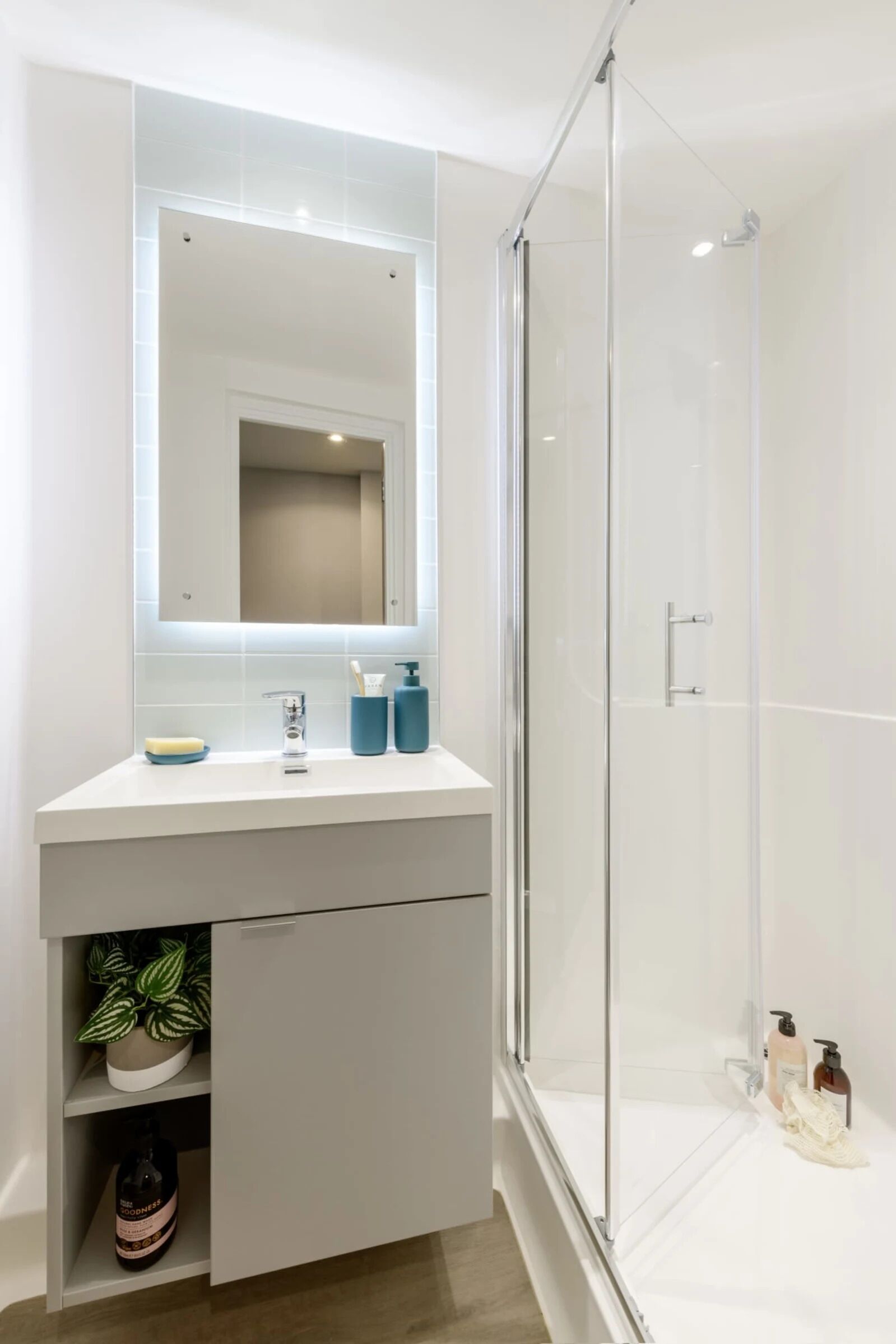 Une salle de bain moderne avec un meuble-lavabo blanc, un grand miroir et une cabine de douche en verre.