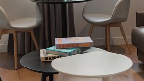 A modern room with a round table, two chairs, a vase with flowers, and books on the table. - Hotel Leev Victoire & Spa (Paris)