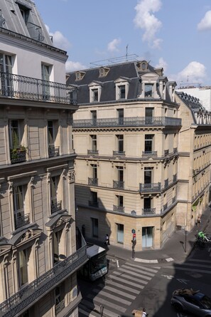 A multi-story building with balconies and a pedestrian crossing. - Hotel Leev Victoire & Spa (Paris)