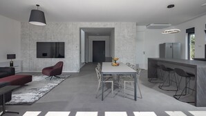 A modern kitchen with a bar area, a dining table with chairs, and a red sofa in a spacious living area.