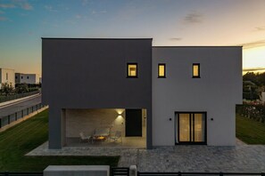 Un bâtiment moderne à deux étages, doté d’un toit plat, de grandes fenêtres et d’un intérieur bien éclairé.