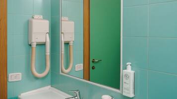 Un bagno con un lavandino bianco, uno specchio e una porta verde.