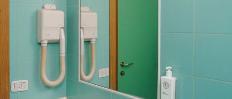 Une salle de bain avec un lavabo blanc, un miroir et une porte verte.
