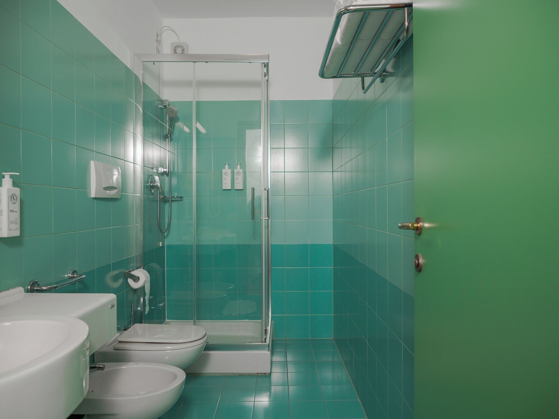 Et badeværelse med brusebad, toilet og håndvask.