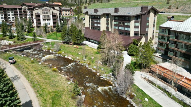 Un complesso alberghiero con diversi edifici, un fiume e montagne sullo sfondo.