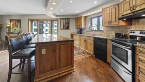 Una cucina moderna con mobili in legno, un'isola centrale, una lavastoviglie e un fornello.